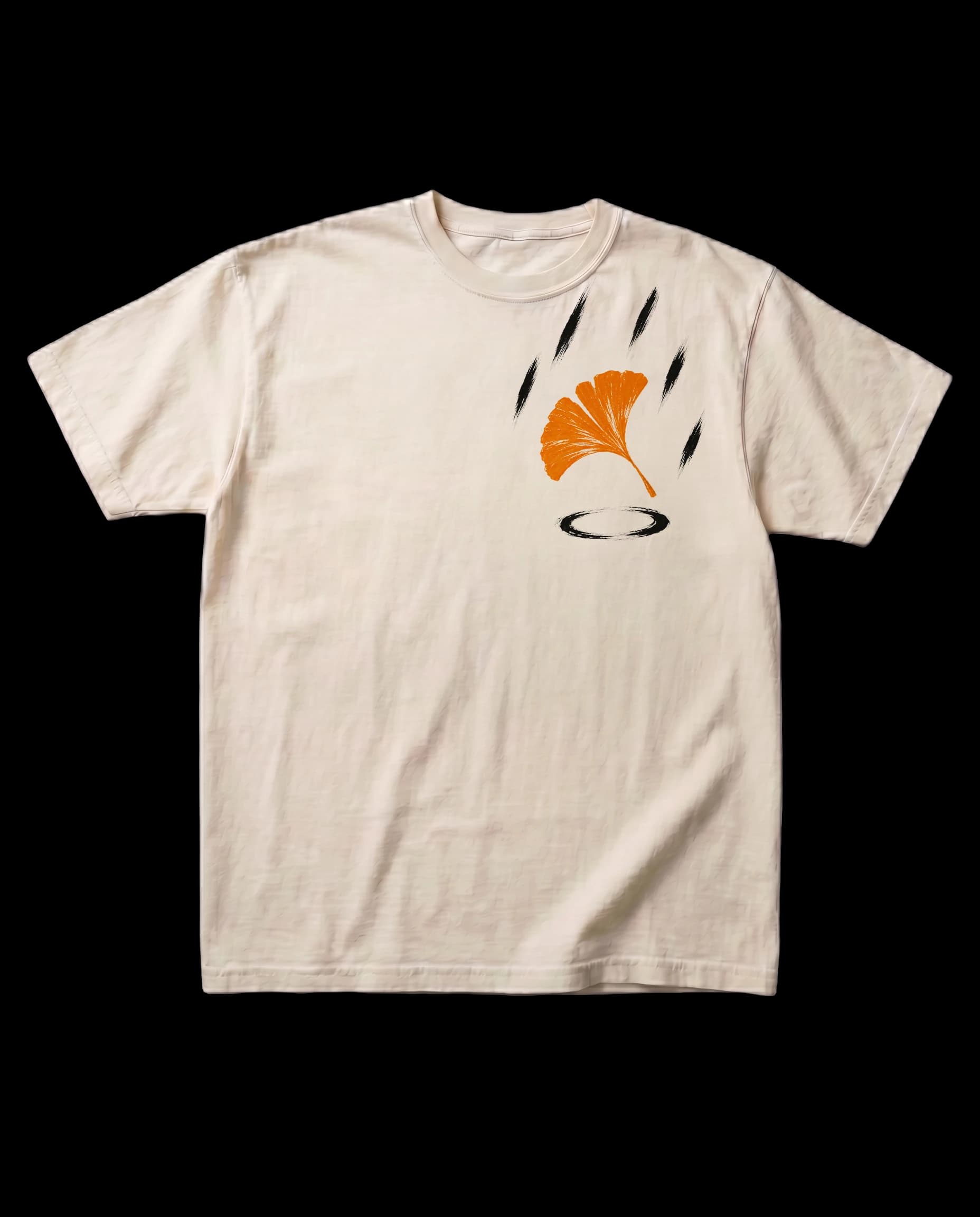 The Ginkgo, Rain tee in Bone, laid flat, with a small print on the left chest: an orange ginkgo leaf falling through bold brushed rain strokes, with an ink ripple below.