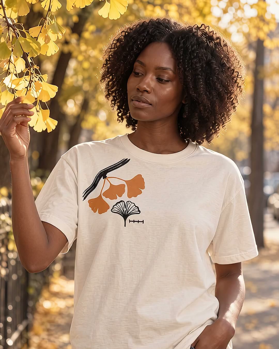 The Ginkgo Study tee in Bone, laid flat, with a print on the right chest: an ink ginkgo branch with three orange leaves, a line-drawn leaf study, and a small scale bar.